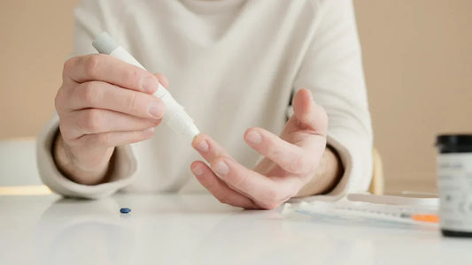 Person führt mit einem Lanzettenstift einen Fingerbluttest zur Selbstmessung durch.