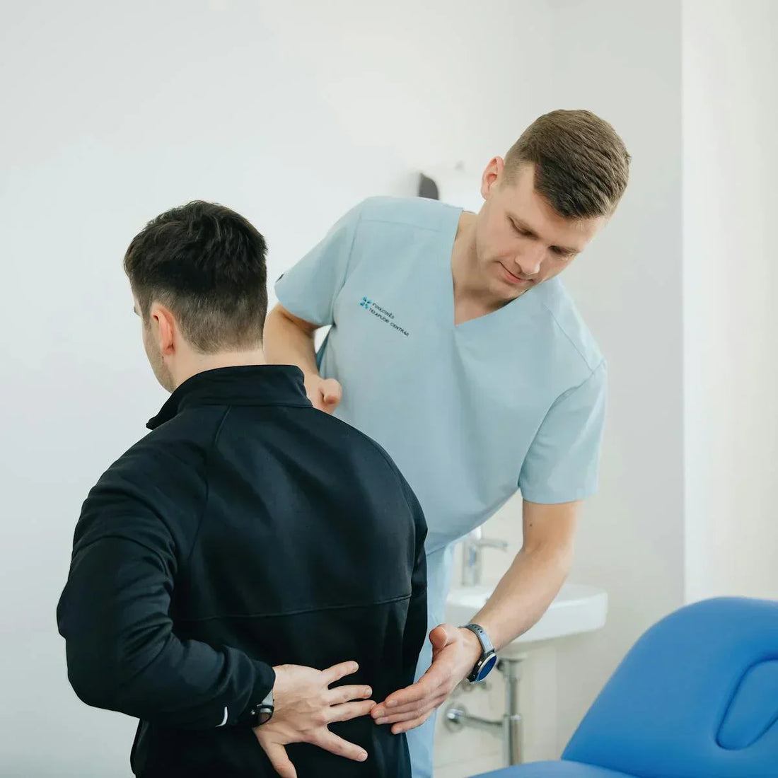 Arzt untersucht einen Patienten mit Rückenschmerzen in einer medizinischen Praxis.