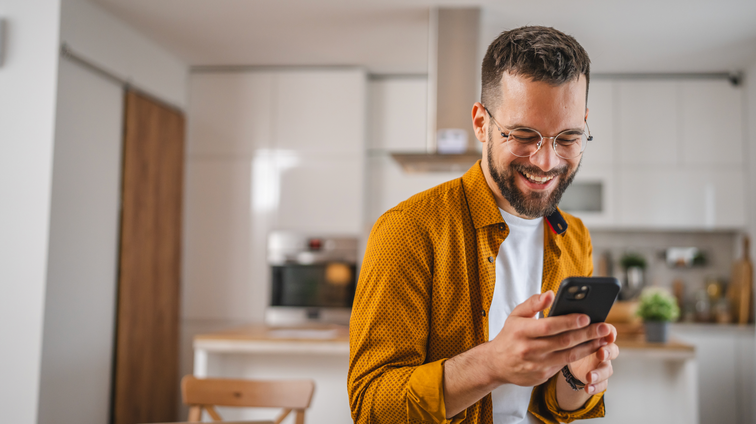 Lachender Mann der glücklich auf sein Smartphone blickt