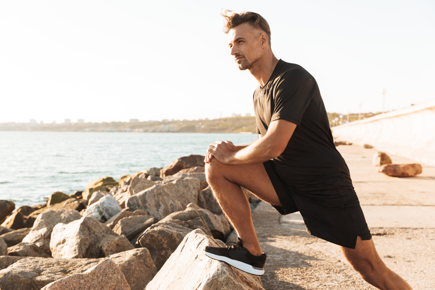 Mann, der sich beim Sport am Meer dehnt