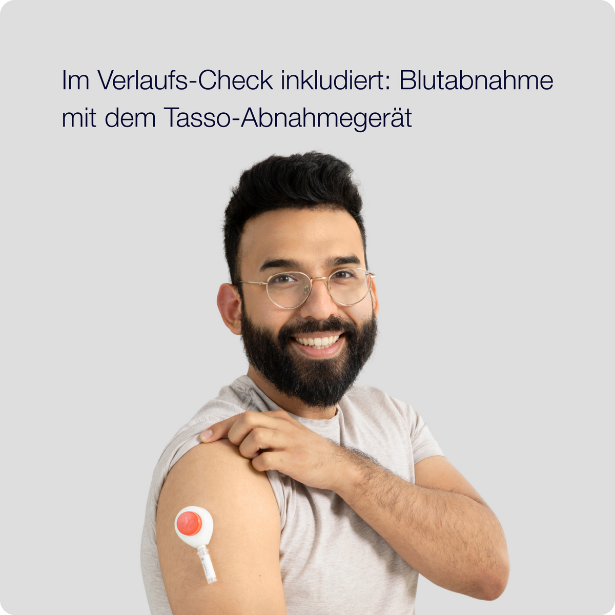 Lächelnder Mann mit Tasso-Gerät am Oberarm bei der Blutabnahme zu Hause für den Verlaufs-Check